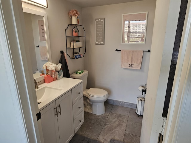 bathroom with toilet, vanity, and baseboards