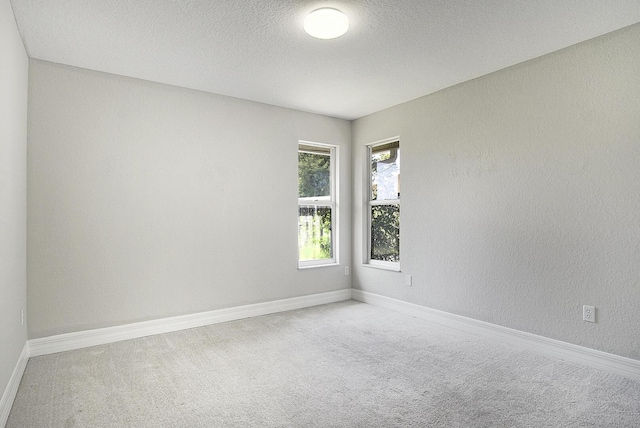 unfurnished room featuring a textured ceiling, a textured wall, carpet, and baseboards