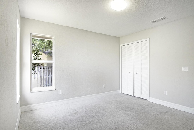 unfurnished bedroom featuring baseboards, carpet, visible vents, and a closet