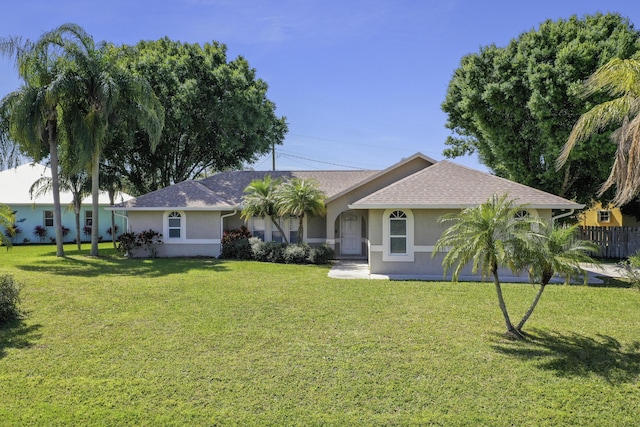 view of front of property featuring roof with shingles, fence, a front lawn, and stucco siding