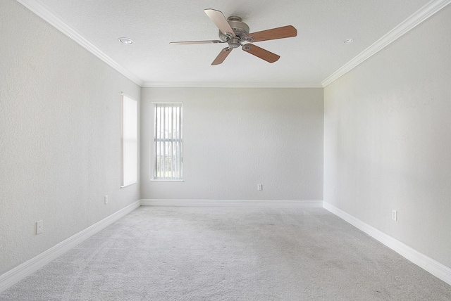 spare room with a ceiling fan, carpet, baseboards, and crown molding