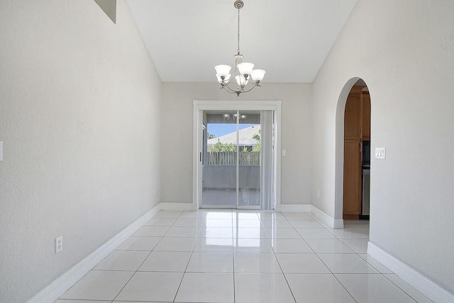 spare room featuring light tile patterned floors, baseboards, arched walkways, lofted ceiling, and an inviting chandelier