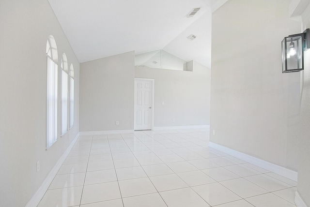 spare room featuring lofted ceiling, light tile patterned floors, baseboards, and visible vents