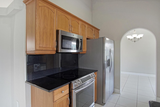 kitchen with dark countertops, baseboards, appliances with stainless steel finishes, and light tile patterned flooring