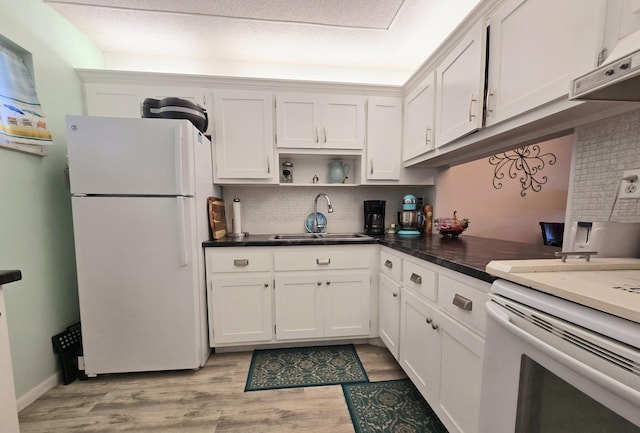 kitchen featuring dark countertops, decorative backsplash, freestanding refrigerator, and a sink