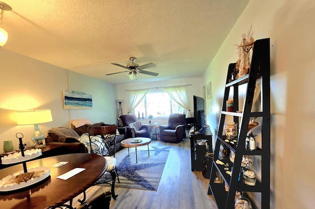 living room with a textured ceiling, a ceiling fan, and wood finished floors