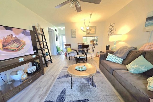 living area with wood finished floors and ceiling fan with notable chandelier