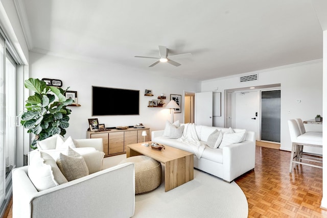 living area with visible vents, a ceiling fan, and ornamental molding