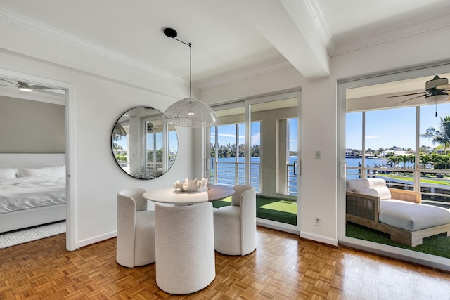 dining space featuring a water view, baseboards, a ceiling fan, and crown molding