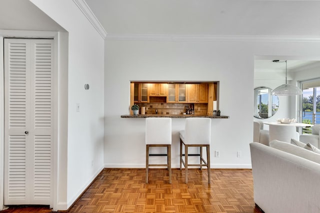 kitchen featuring baseboards, decorative backsplash, glass insert cabinets, a kitchen breakfast bar, and crown molding