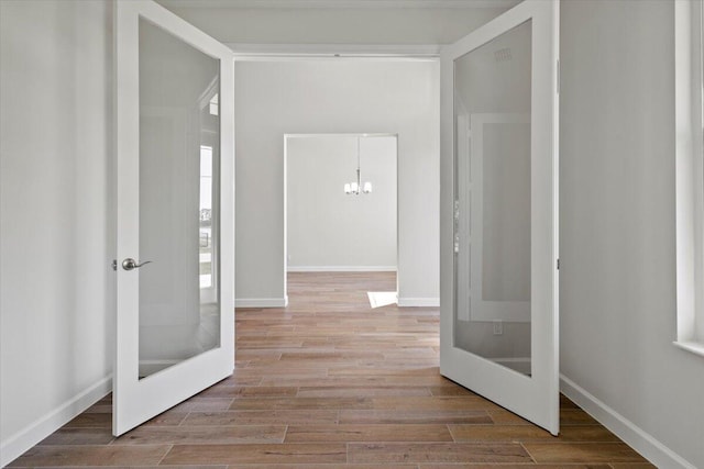 corridor with baseboards, wood finished floors, and french doors