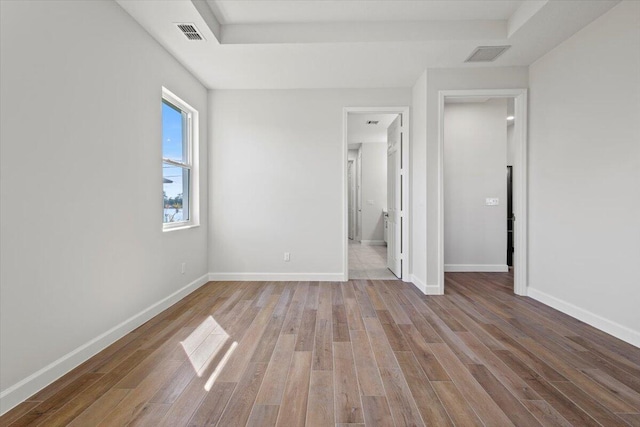 unfurnished bedroom with wood finished floors, visible vents, and baseboards