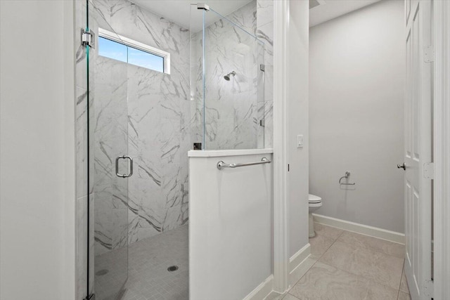 bathroom featuring baseboards, toilet, and a marble finish shower