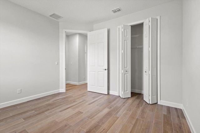 unfurnished bedroom with a closet, visible vents, light wood-style flooring, and baseboards