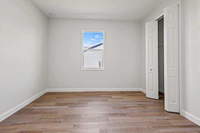 unfurnished bedroom featuring light wood-type flooring and baseboards