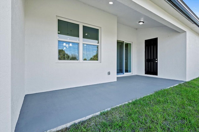 view of exterior entry with a patio area and stucco siding