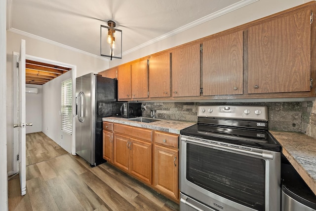 kitchen with ornamental molding, a sink, stainless steel appliances, light wood finished floors, and decorative backsplash