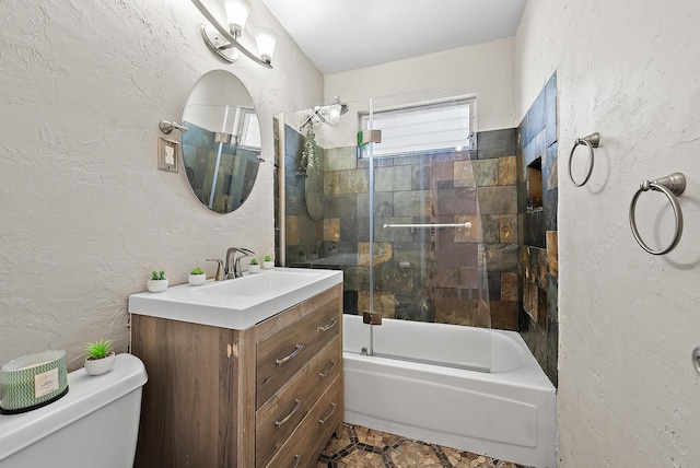 full bath featuring vanity, toilet, a textured wall, and enclosed tub / shower combo