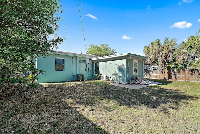 back of property with central air condition unit, a yard, stucco siding, and fence