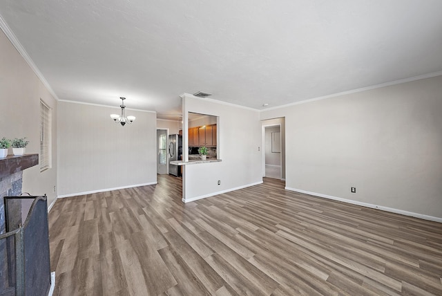 unfurnished living room featuring visible vents, baseboards, an inviting chandelier, and wood finished floors