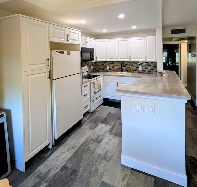 kitchen featuring visible vents, decorative backsplash, a peninsula, white appliances, and a sink