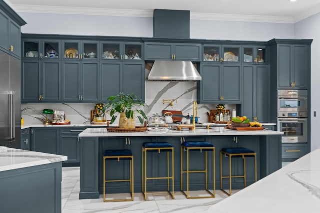 kitchen featuring ventilation hood, a kitchen bar, marble finish floor, and appliances with stainless steel finishes