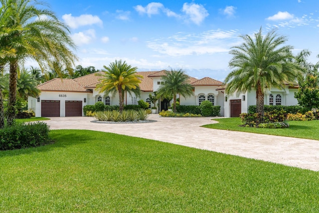 mediterranean / spanish home with decorative driveway, a front lawn, an attached garage, and stucco siding