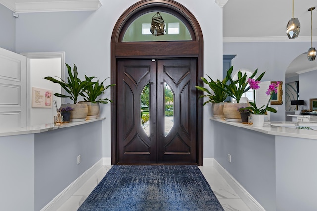 entryway with baseboards, arched walkways, marble finish floor, and ornamental molding