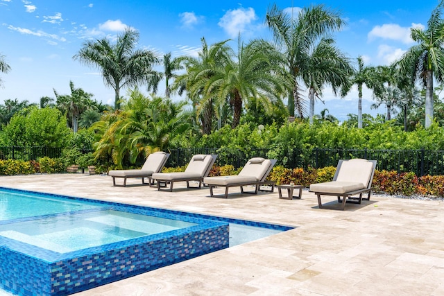 view of pool with a patio area, fence, and a pool with connected hot tub