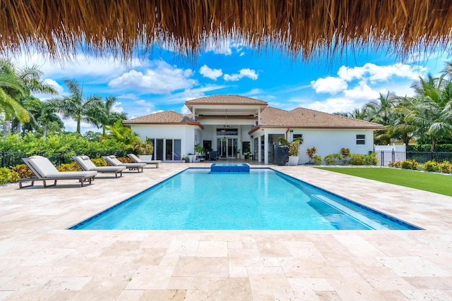 view of pool featuring a patio area, fence, and a pool with connected hot tub