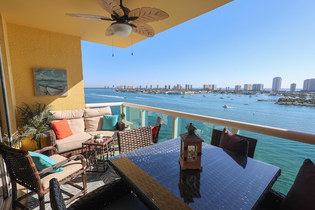 balcony with outdoor dining space, a ceiling fan, an outdoor living space, a water view, and a city view