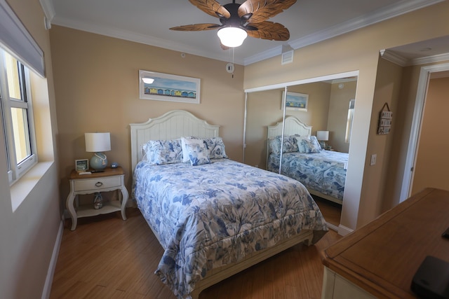 bedroom featuring a ceiling fan, baseboards, wood finished floors, visible vents, and ornamental molding