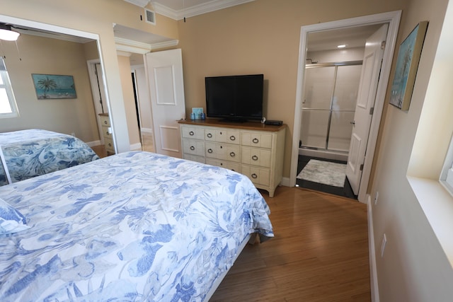 bedroom with visible vents, baseboards, ornamental molding, wood finished floors, and ensuite bath