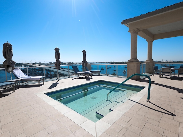 view of swimming pool with a patio, a water view, and a hot tub