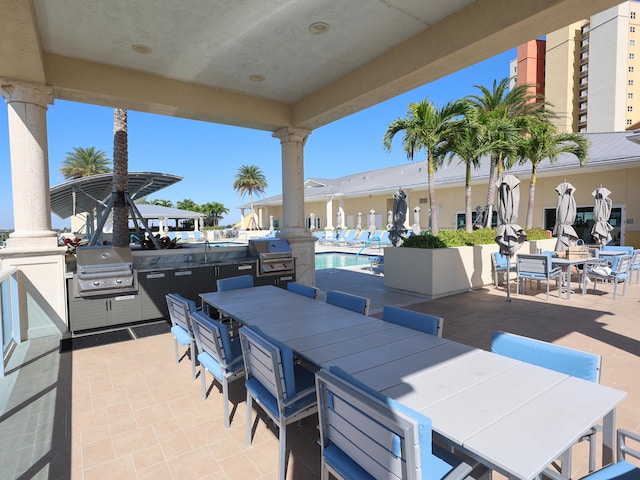 view of patio featuring outdoor dining area, a community pool, an outdoor kitchen, and grilling area