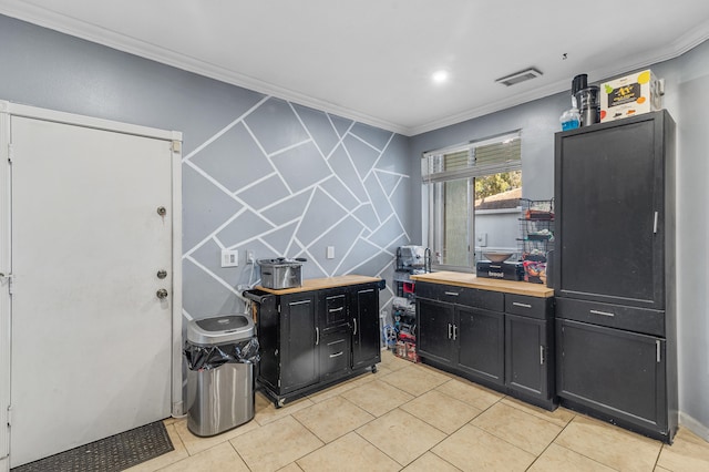 kitchen featuring light tile patterned flooring, dark cabinets, butcher block counters, visible vents, and ornamental molding