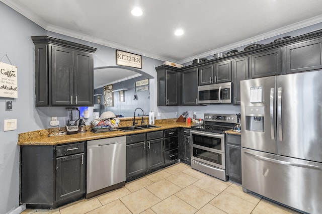 kitchen featuring light tile patterned floors, dark cabinets, a sink, ornamental molding, and appliances with stainless steel finishes