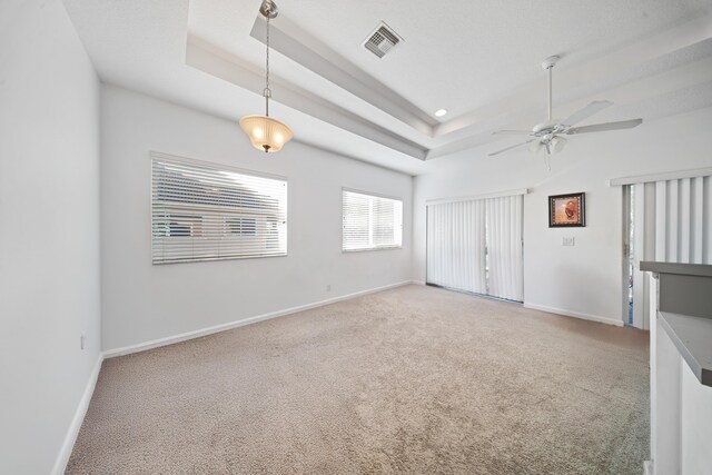 carpeted spare room featuring visible vents, a tray ceiling, recessed lighting, baseboards, and ceiling fan