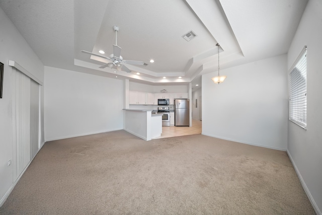 unfurnished living room with visible vents, recessed lighting, baseboards, a raised ceiling, and light colored carpet