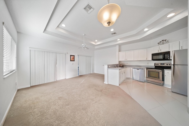 kitchen with visible vents, open floor plan, stainless steel appliances, white cabinetry, and a raised ceiling