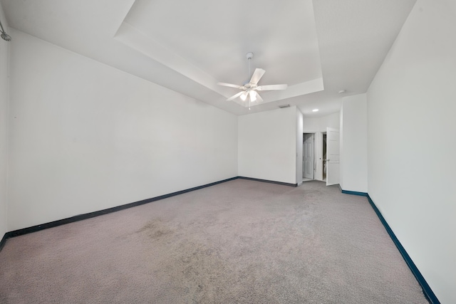 carpeted empty room with baseboards, a raised ceiling, and a ceiling fan