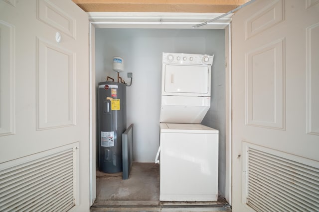 clothes washing area featuring laundry area, stacked washer / drying machine, and electric water heater