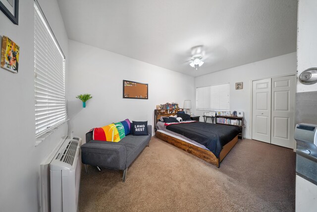 carpeted bedroom with a closet, multiple windows, radiator heating unit, and ceiling fan