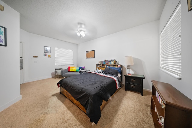 bedroom with light colored carpet, baseboards, and a textured ceiling