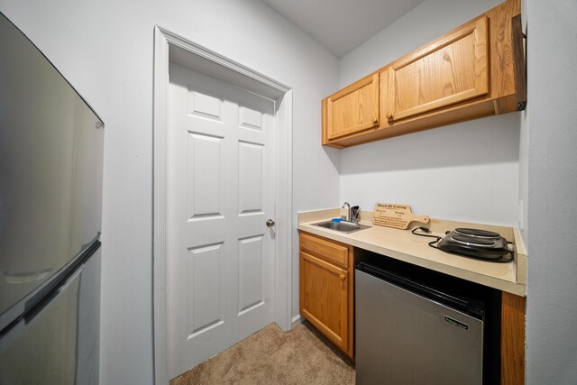 kitchen featuring a sink, light colored carpet, appliances with stainless steel finishes, and light countertops