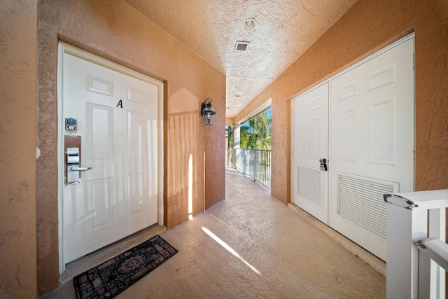 interior space with unfinished concrete floors, a textured ceiling, and a textured wall