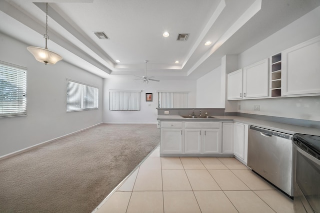 kitchen featuring visible vents, a sink, light carpet, dishwasher, and a raised ceiling