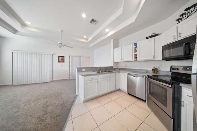 kitchen featuring visible vents, a sink, appliances with stainless steel finishes, light carpet, and a raised ceiling