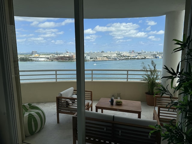 balcony with a view of city, a water view, and an outdoor living space