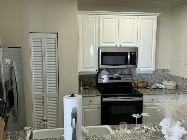 kitchen with dark stone counters, appliances with stainless steel finishes, backsplash, and white cabinetry